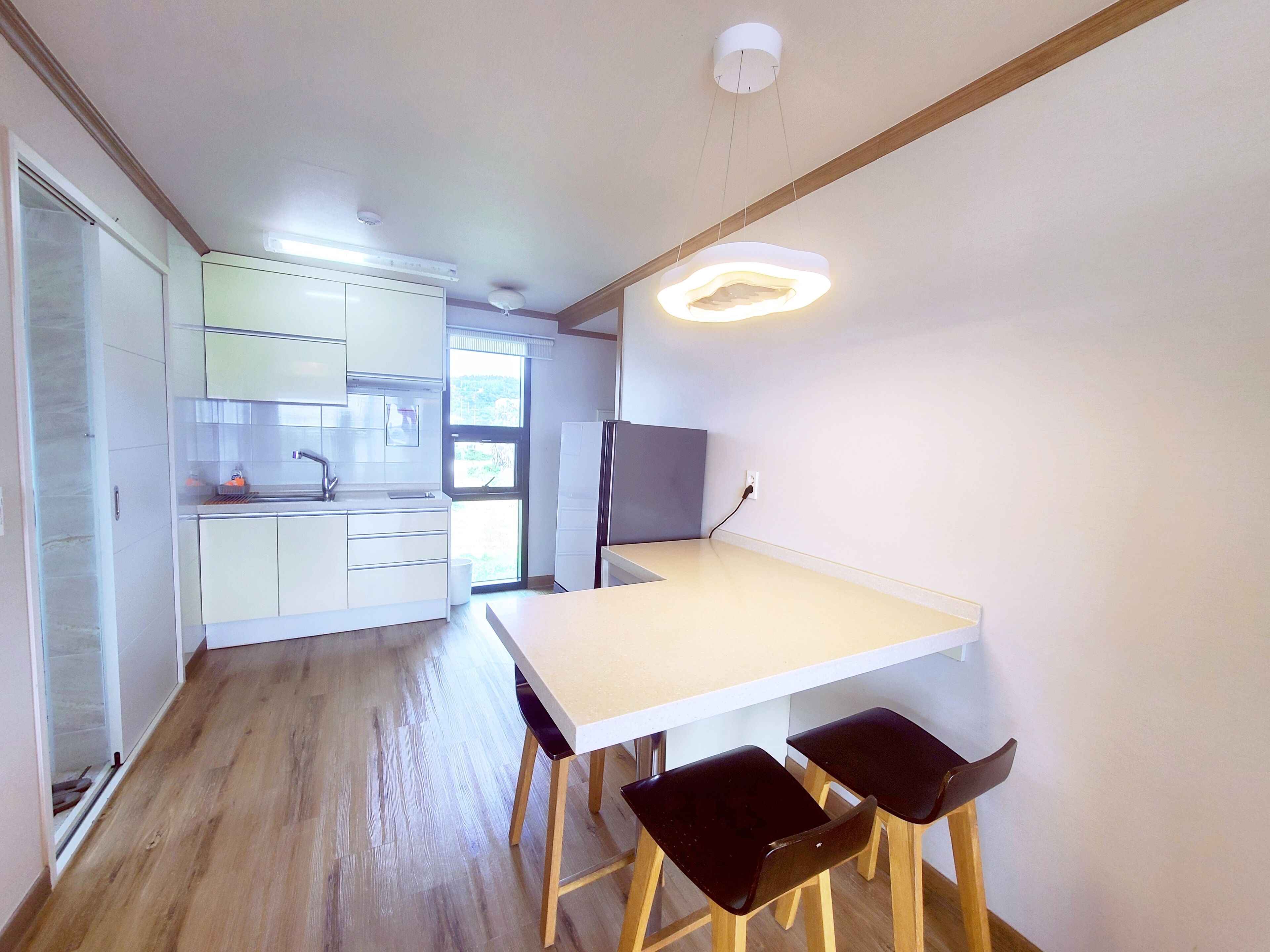 Une cuisine moderne avec des meubles blancs, un plan de travail en bois et un coin repas comprenant une table et des chaises.