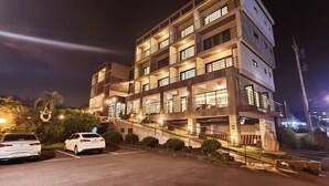 A multi-story building with a parking area in front.