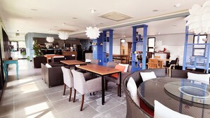 A modern restaurant with round tables, wicker furniture, and blue accents.