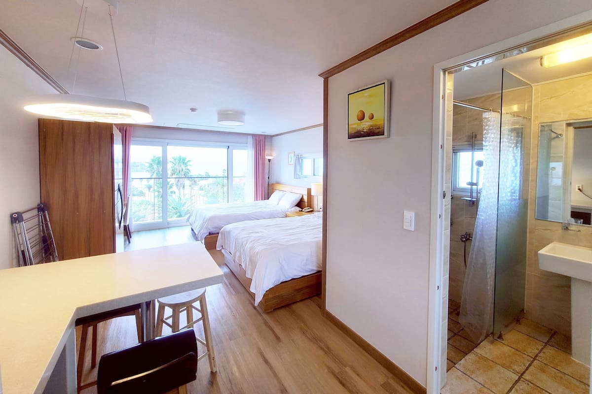 Habitación de hotel con cama, escritorio y zona de ducha.