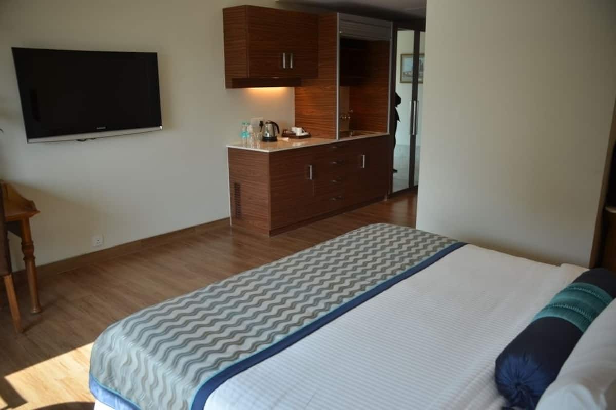 Une chambre à coucher avec un lit, un téléviseur fixé au mur, des armoires en bois et un miroir.