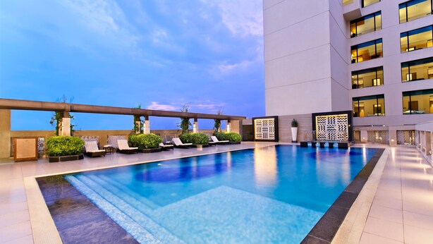 A rooftop swimming pool with lounge chairs and a view of the city skyline. - The Lalit Traveller Jaipur (Jaipur)