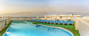 A rooftop swimming pool with blue lounge chairs and a view of the sea. - Cerviola Hotel (Marsaskala)
