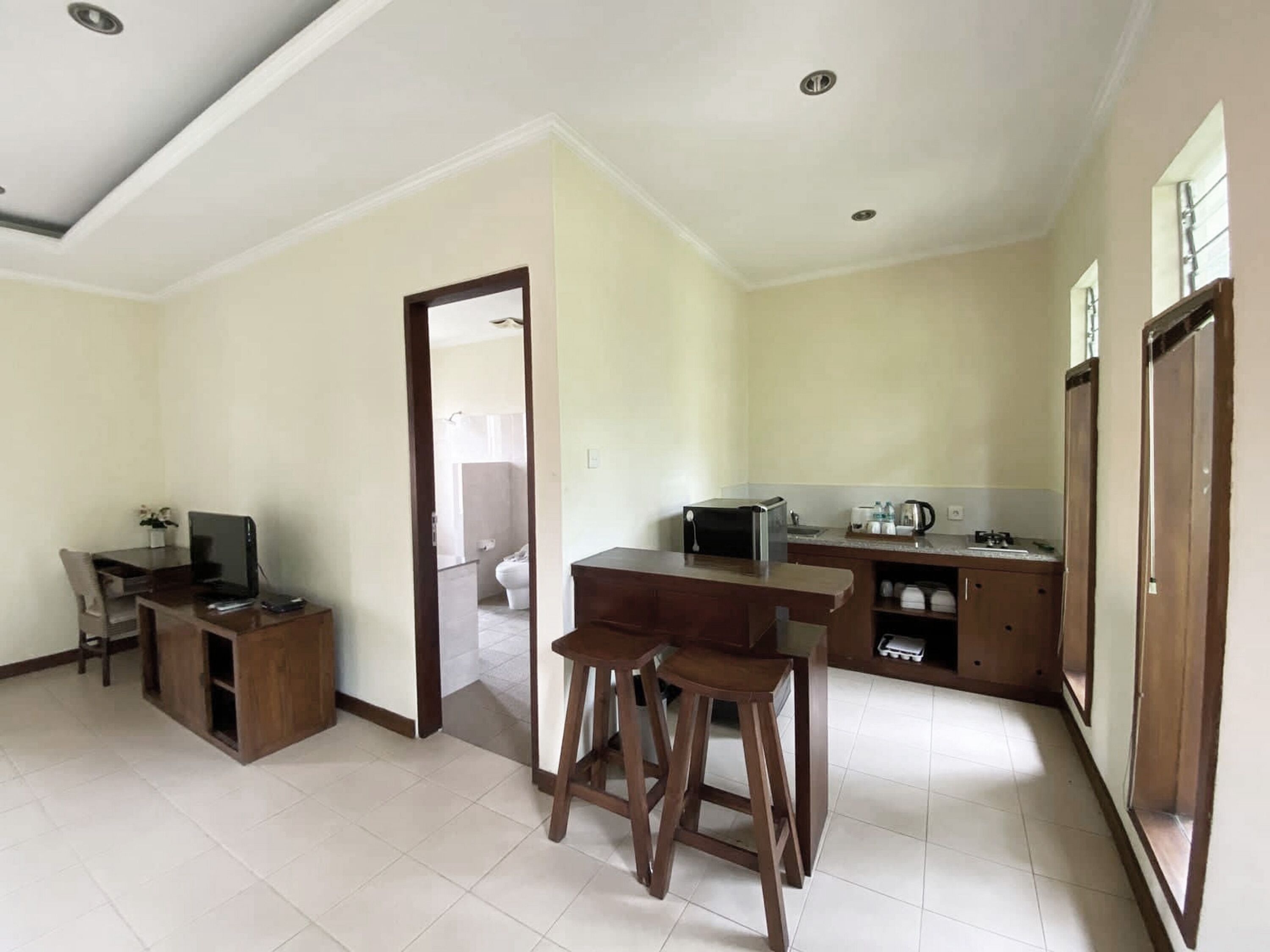 A spacious living area with a dining table and chairs, a kitchenette, and a view into the adjacent bathroom.