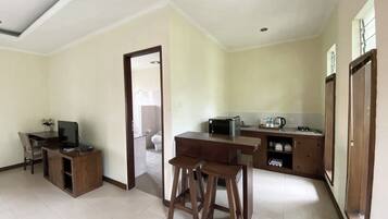 A spacious living area with a dining table and chairs, a kitchenette, and a view into the adjacent bathroom.