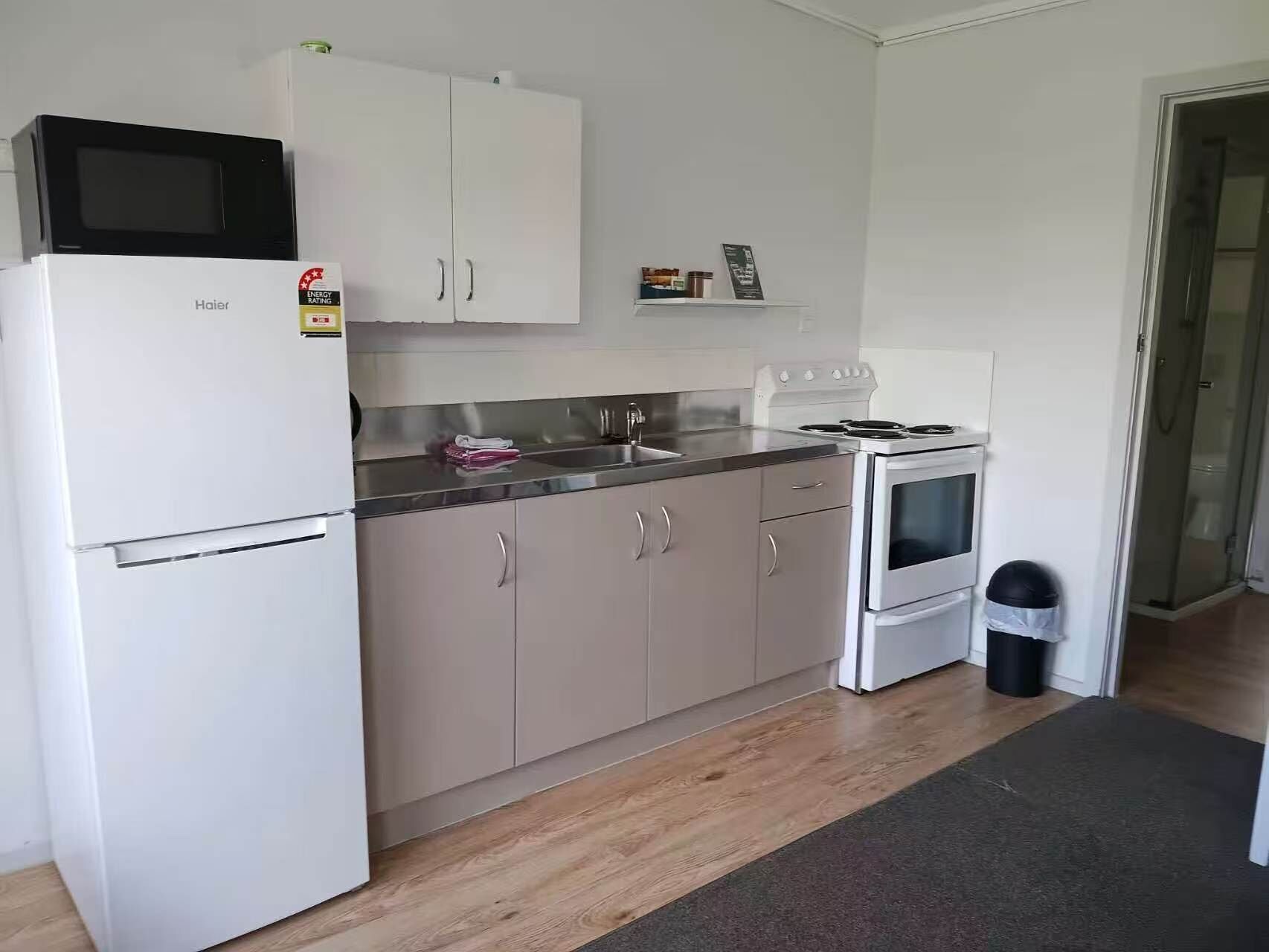 A compact kitchen with a refrigerator, microwave, stove, and sink.