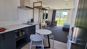 Una cocina moderna con un lavamanos, estufa y comedor con sillas y una mesa.