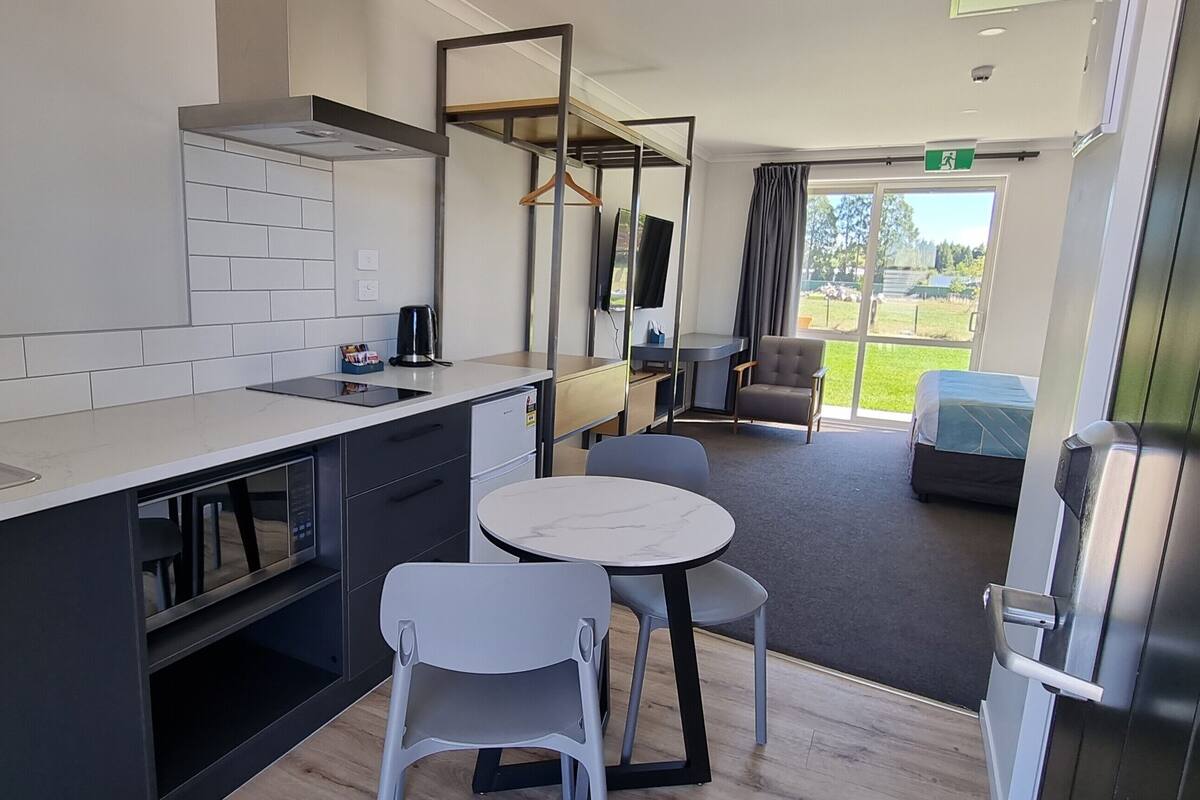 A modern kitchen with a sink, stove, and dining area with chairs and a table.