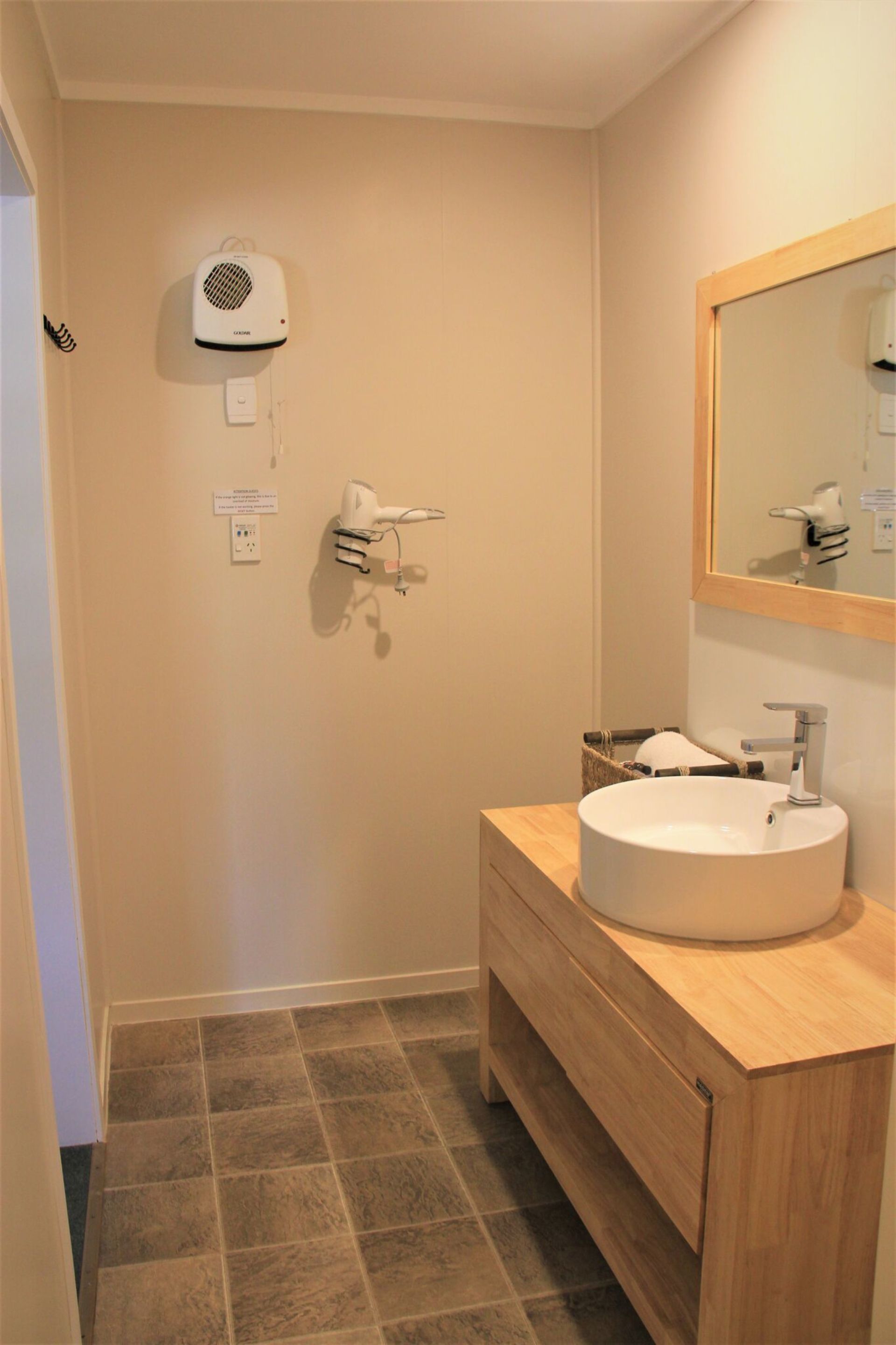 A bathroom with a sink, mirror, and hairdryer mounted on the wall.