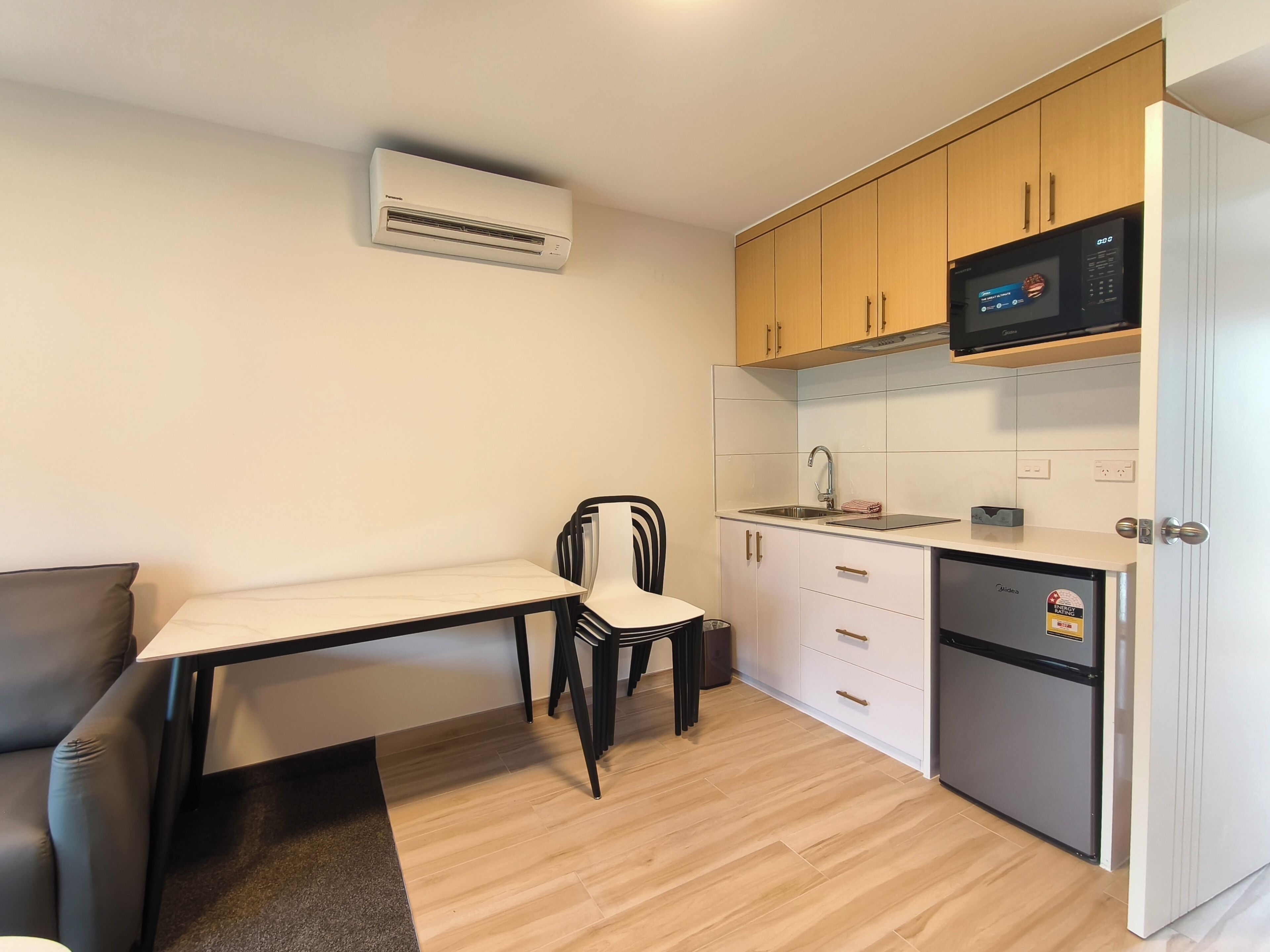 A compact kitchen with a dining table, chairs, a microwave, and a refrigerator.