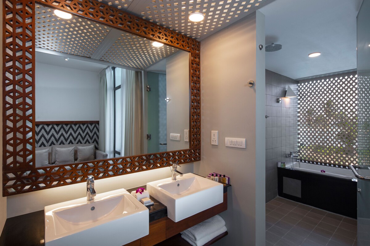 A modern bathroom with two sinks, a large mirror, and a shower area.