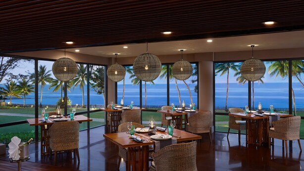 A restaurant with tables set for dining, large windows with a view of the ocean, and hanging spherical light fixtures. - Cinnamon Bey Beruwala (Beruwala)