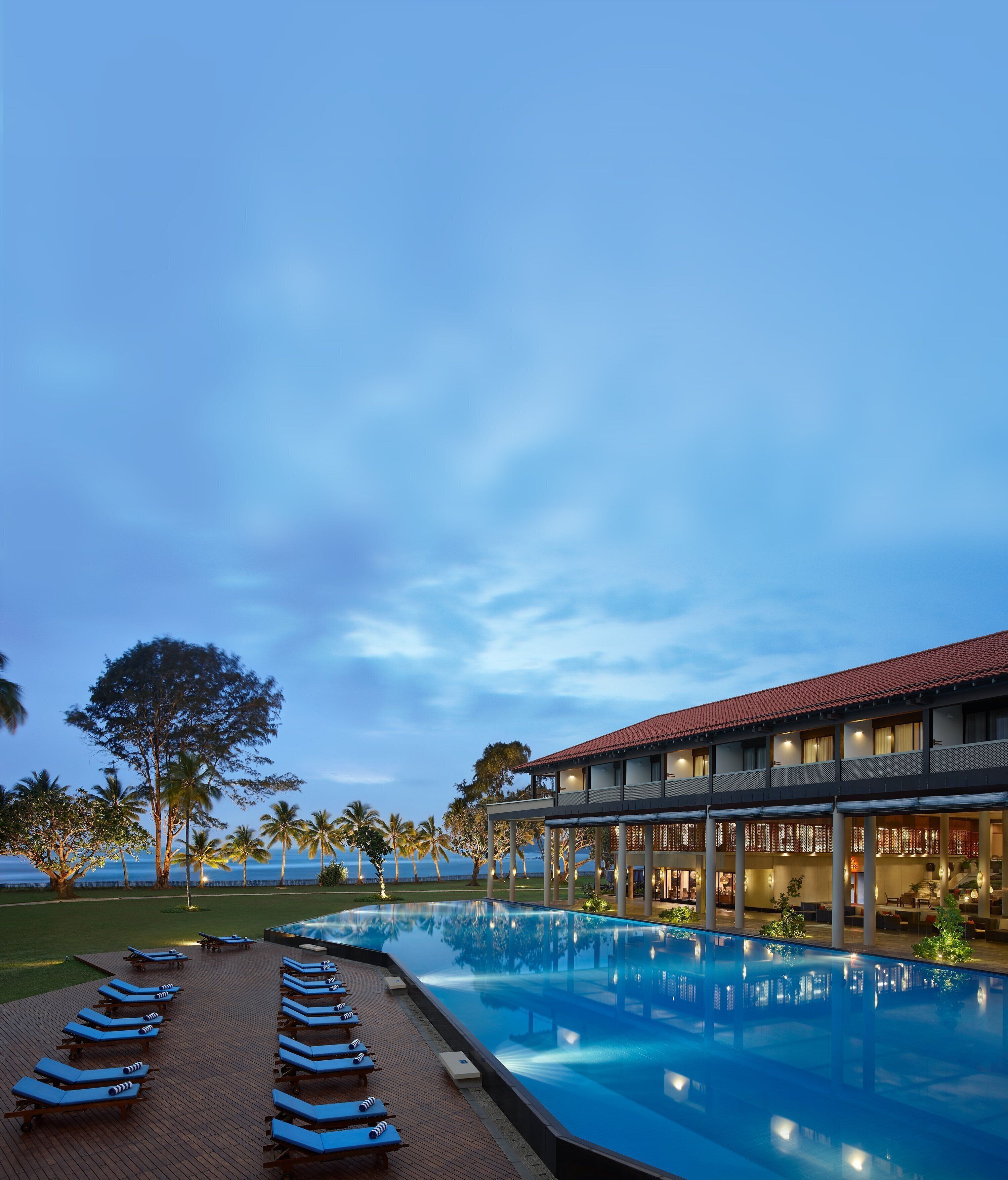 A pool area with lounge chairs and a building with a red roof.