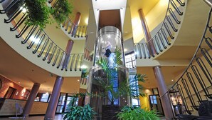 A multi-level atrium with a central spiral staircase, multiple staircases on each level, and several potted plants.