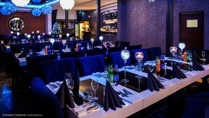 A restaurant with tables set for dining, featuring blue chairs and crystal chandeliers.