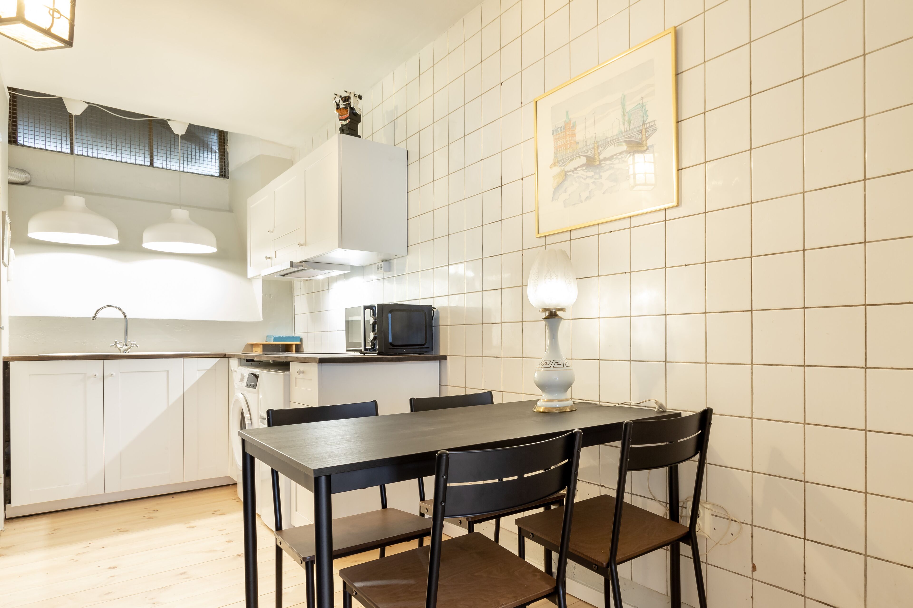 A compact kitchen with white cabinets, a microwave, and a dining table with chairs.