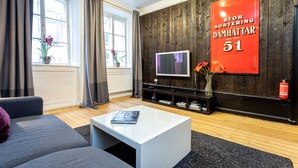 A modern living room with a white coffee table, grey sofa, and a TV on a wooden wall.