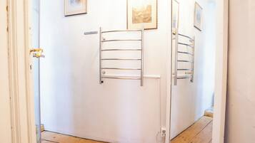A hallway with a white door, a metal towel rack, and a framed picture on the wall.