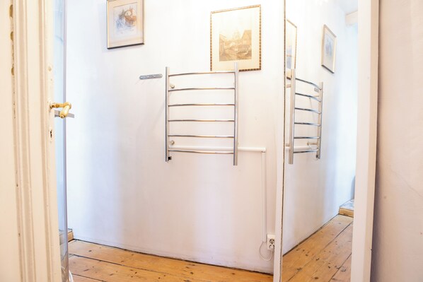 A hallway with a white door, a metal towel rack, and a framed picture on the wall.
