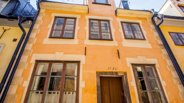 A building with a yellow facade, multiple windows, and a door marked with the number 50.