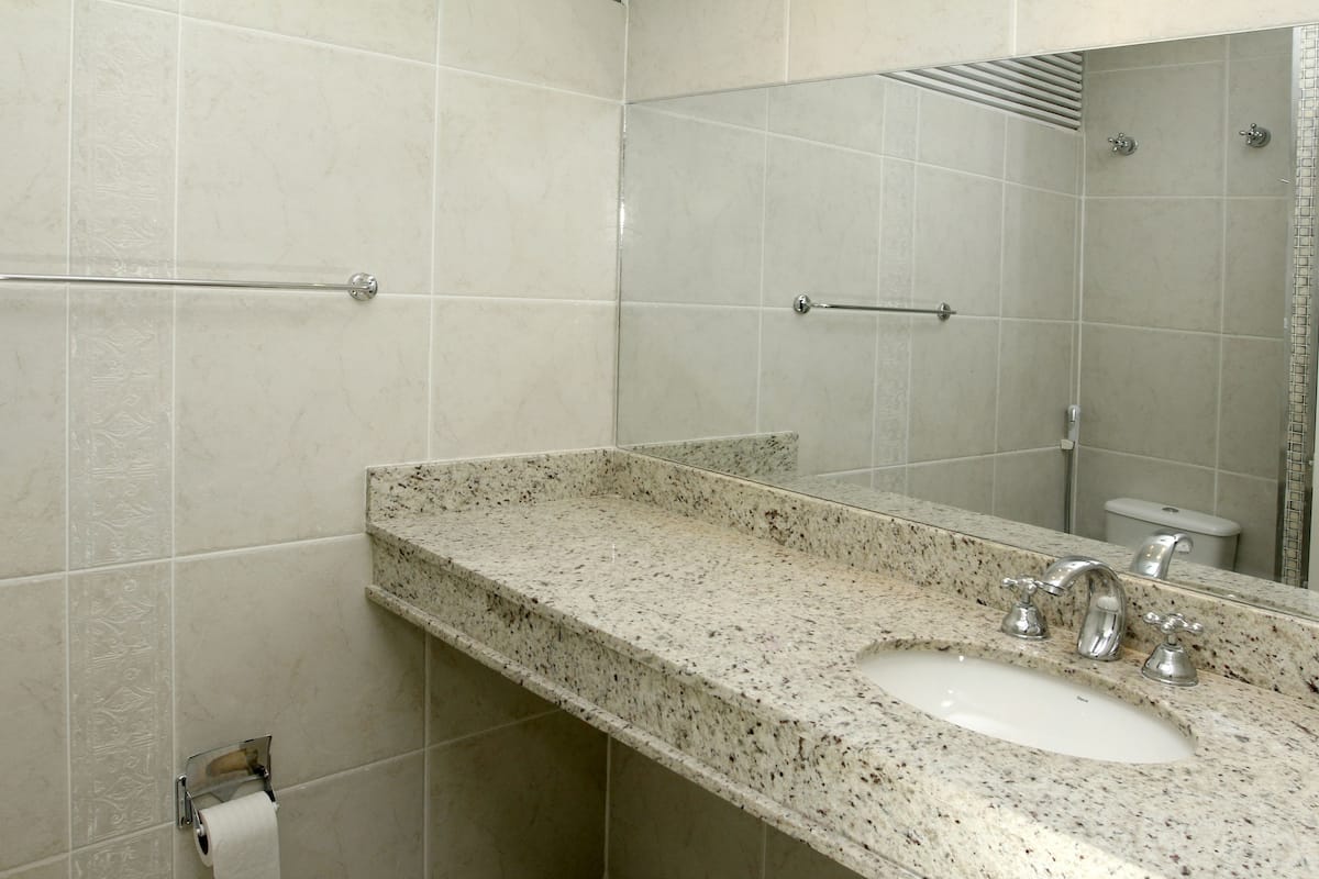 A bathroom with a granite countertop, a sink, and a mirror.