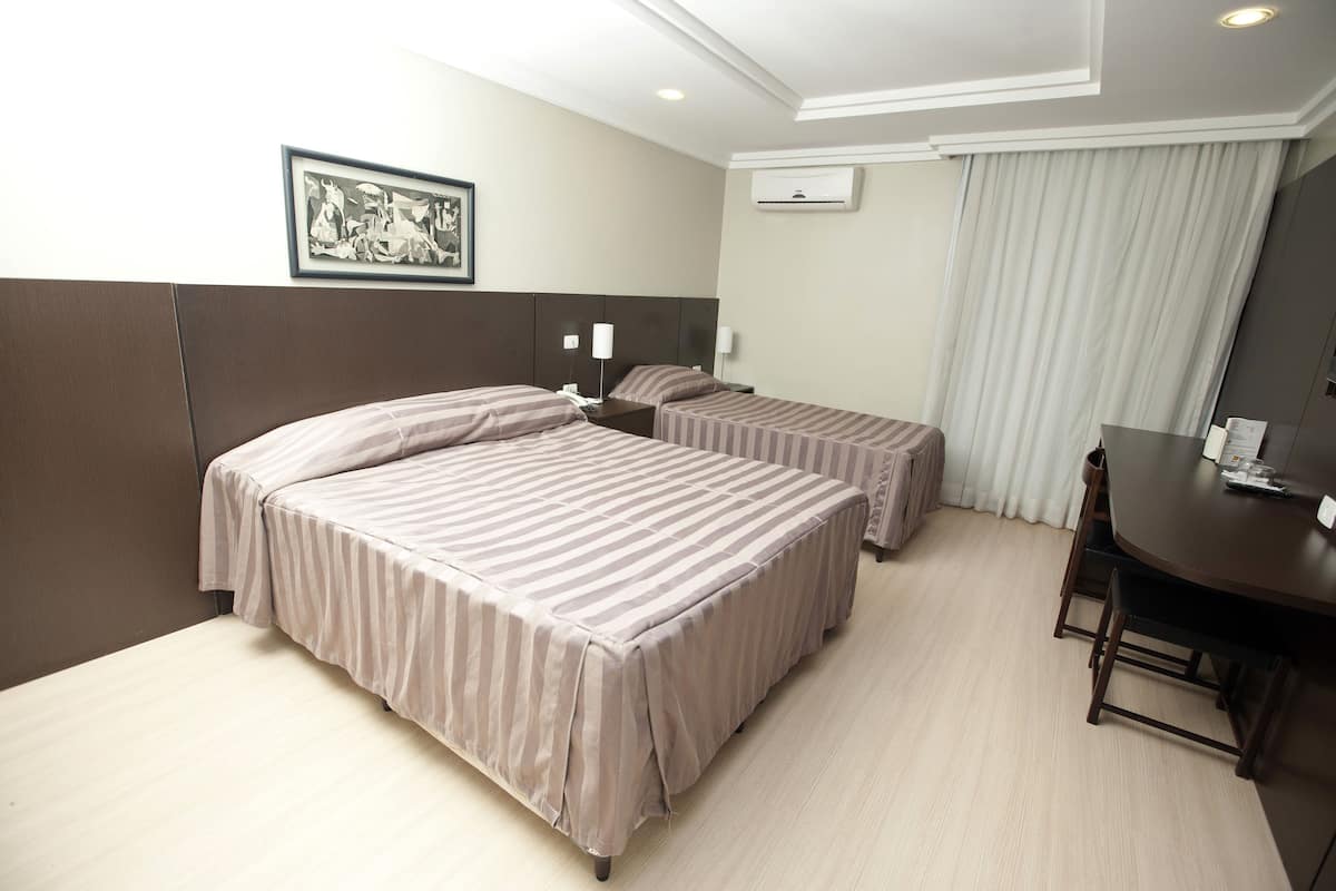 A hotel room with two beds, a desk, and a chair.