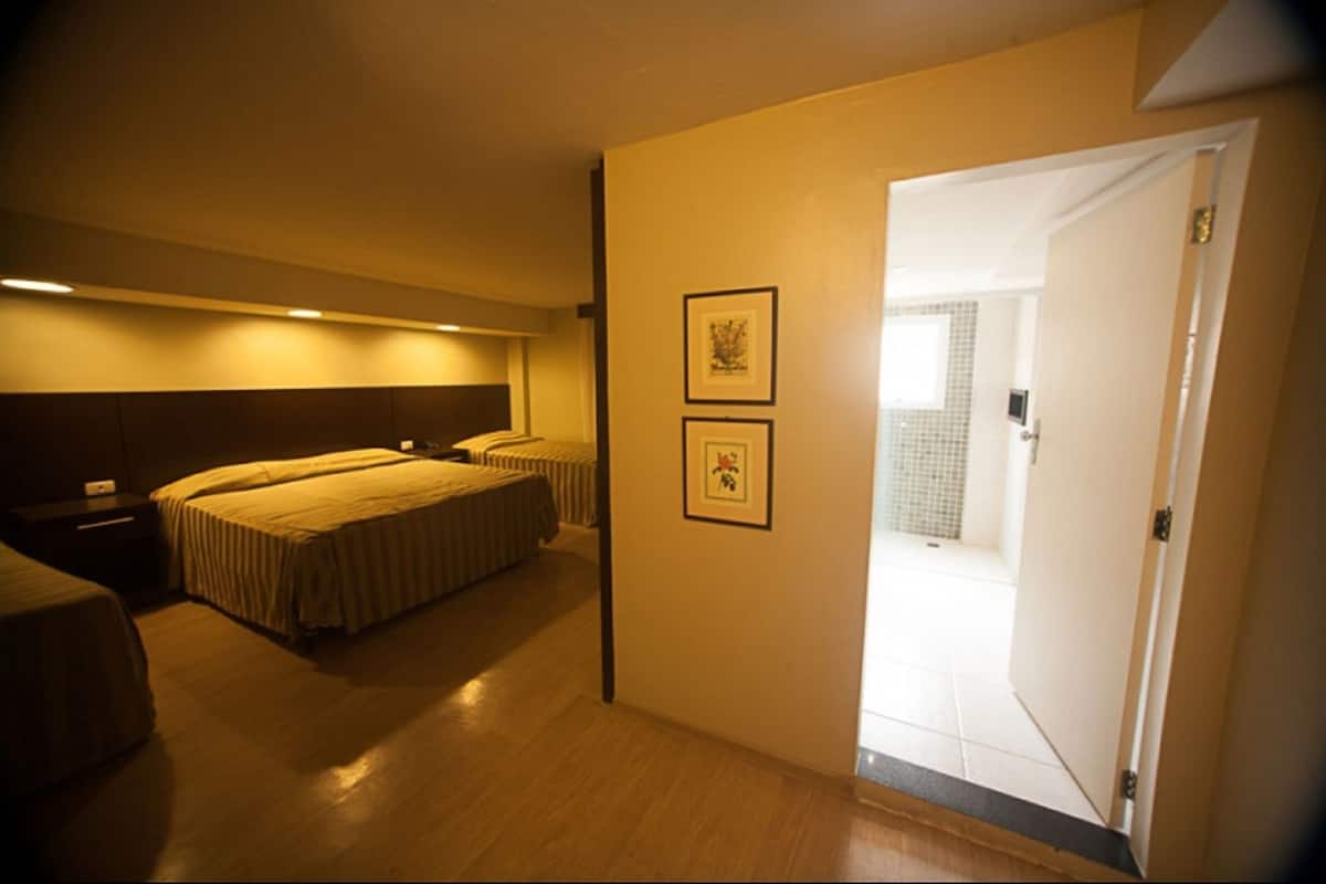 A hotel room with a bed, bedside tables, and two framed pictures on the wall.