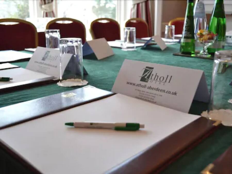 A conference table with name cards, pens, and glassware.