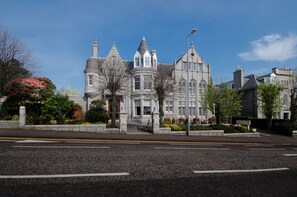 A historic building with a turret and multiple windows, surrounded by landscaped gardens and a paved street. - Atholl Hotel (Aberdeen)