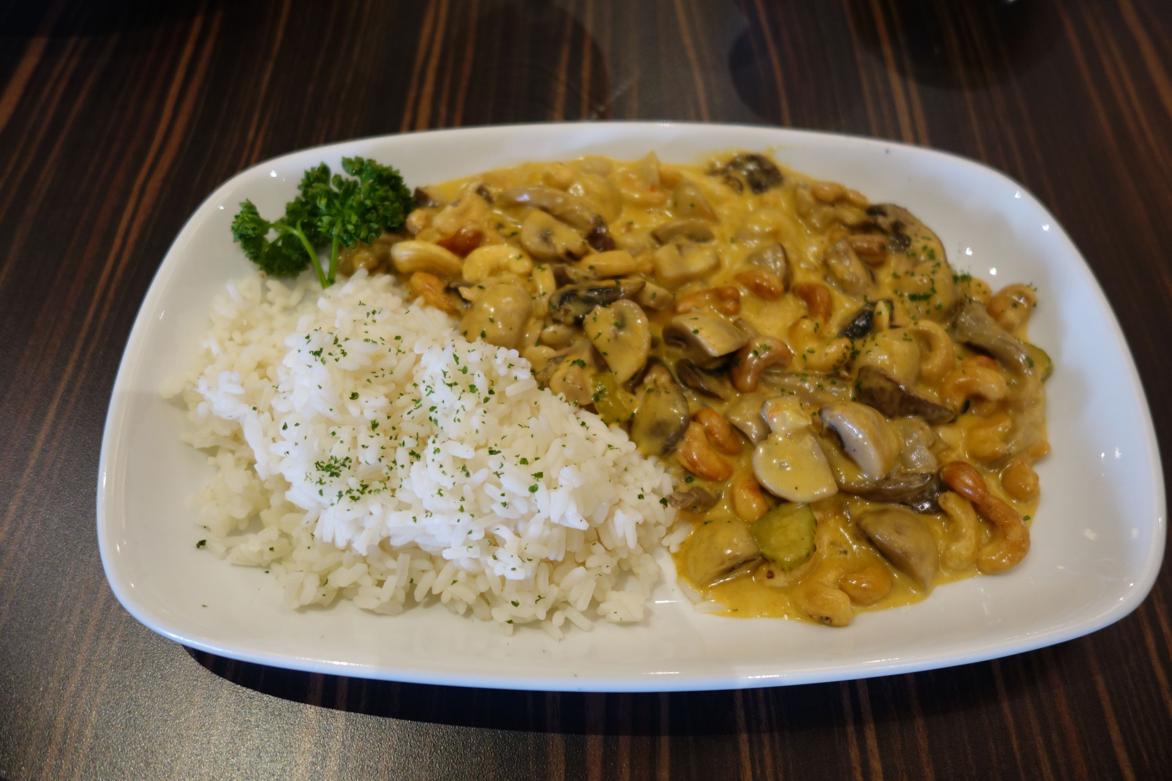 A plate of white rice and a creamy mushroom dish on a white plate.