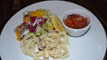 A plate with a salad, a lemon wedge, and a bowl of salsa.