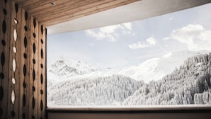 Een houten interieur met een raam dat uitkijkt op een besneeerd berglandschap.