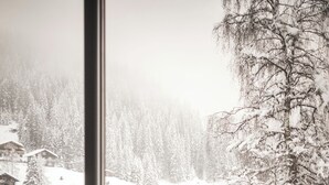 Een eetruimte met uitzicht op een besneeuwd landschap door een groot raam.