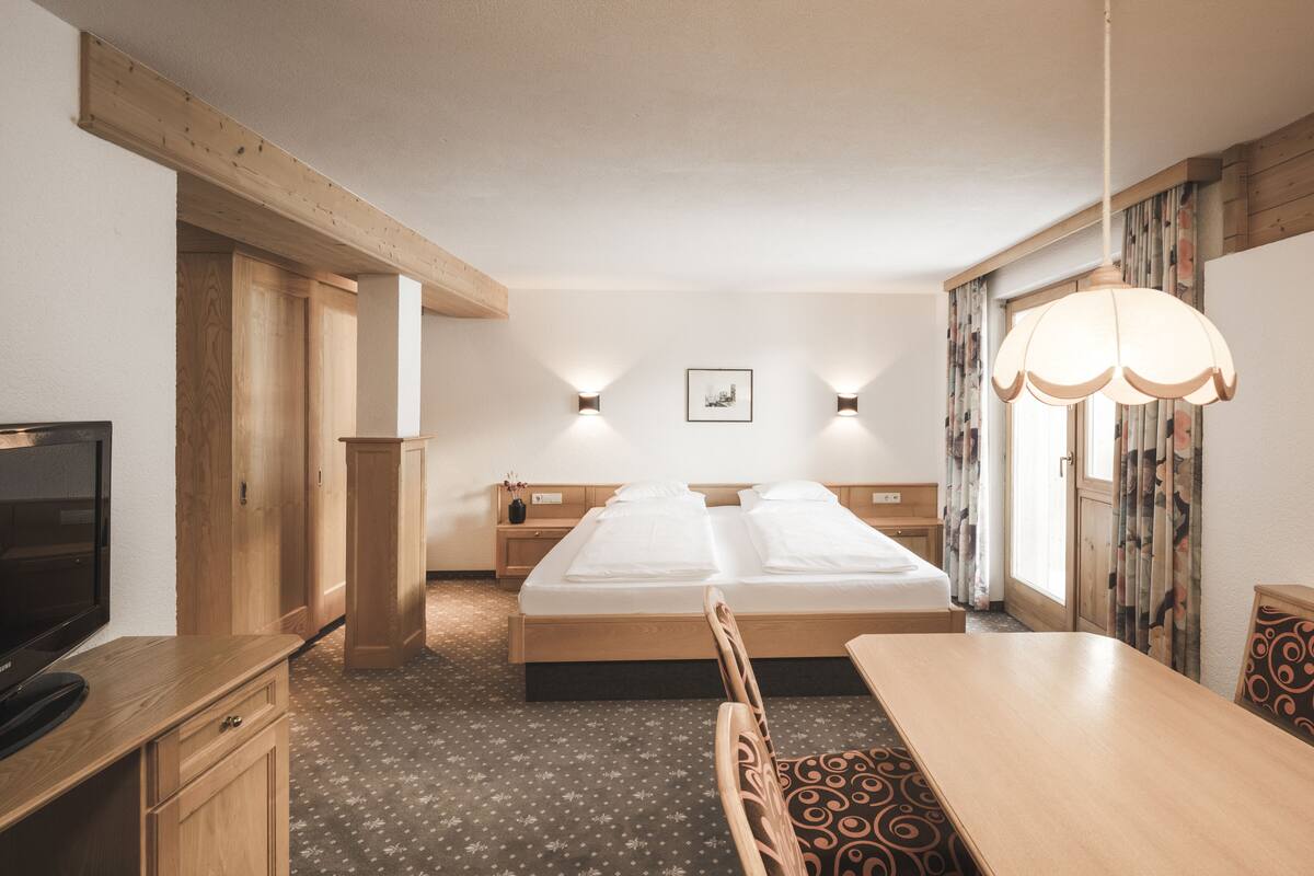 Ein Hotelzimmer mit Bett, Nachttischen, Fernseher, Esstisch und Stuhl.