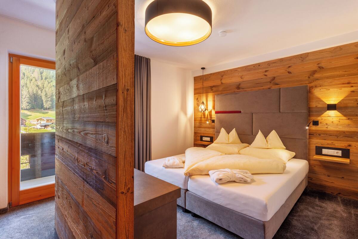 Ein modernes Schlafzimmer mit einer Holzpaneelausstattung, einem Bett mit weißer Bettwäsche und einem Nachttisch.