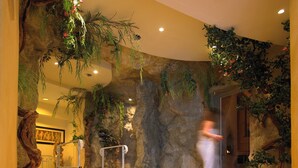 Een wellnessruimte met een stenen muur, planten en een betegelde vloer.