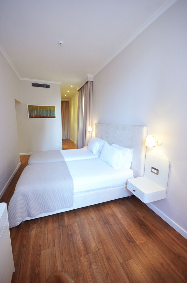A hotel room with a large bed, a bedside table, a lamp, and a painting on the wall.