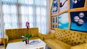 Un sofá amarillo y una mesa blanca con revistas y una planta en maceta.