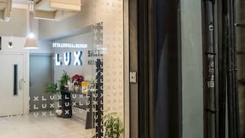 La entrada del Hotel LUX Santiago, con un llamativo letrero iluminado y una fachada moderna y limpia.
