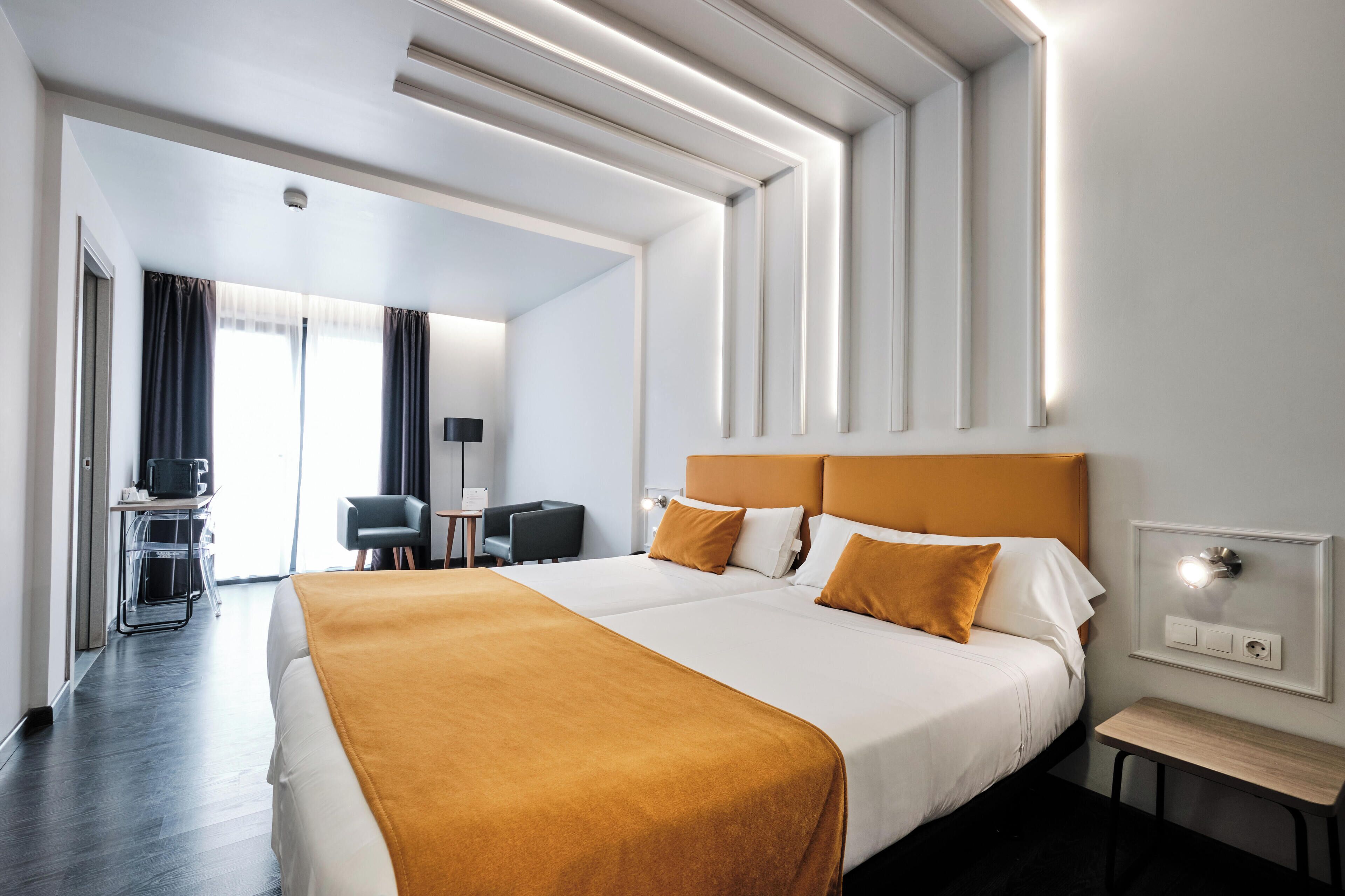 Una habitación de hotel con una cama grande, un escritorio, una silla y una lámpara de escritorio.