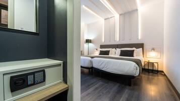 A modern hotel room with a control panel, a double bed, bedside tables, and a wall-mounted light fixture.