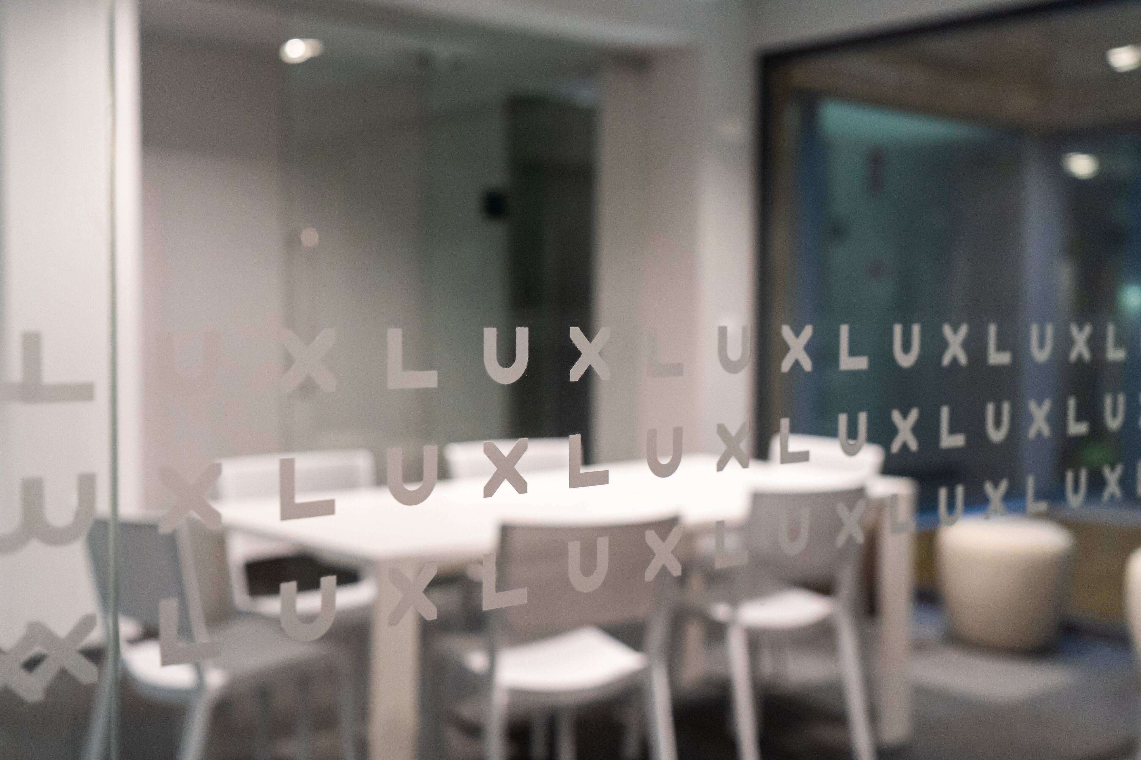A modern interior with white tables and chairs, a glass wall with 'LUXLUXLUXLUXLUXLUXLUXLUXLUXLUXLUXLUXLUXLUXLUXLUXLUXLUXLUXLUXLUXLUXLUXLUXLUXLUXLUXLUXLUXLUXLUXLUXLUXLUXLUXLUXLUXLUXLUXLUXLUXLUXLUXLUXLUXLUXLUXLUXLUXLUXLUXLUXLUXLUXLUXLUXLUXLUXLUXLUXLUXLUXLUXLUXLUXLUXLUXLUXLUXLUXLUXLUXLUXLUXLUXLUXLUXLUXLUXLUXLUXLUXLUXLUXLUXLUXLUXLUXLUXLUXLUXL