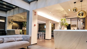 Un interior moderno con techo de vidrio, una recepción, un sofá y una zona de comedor.