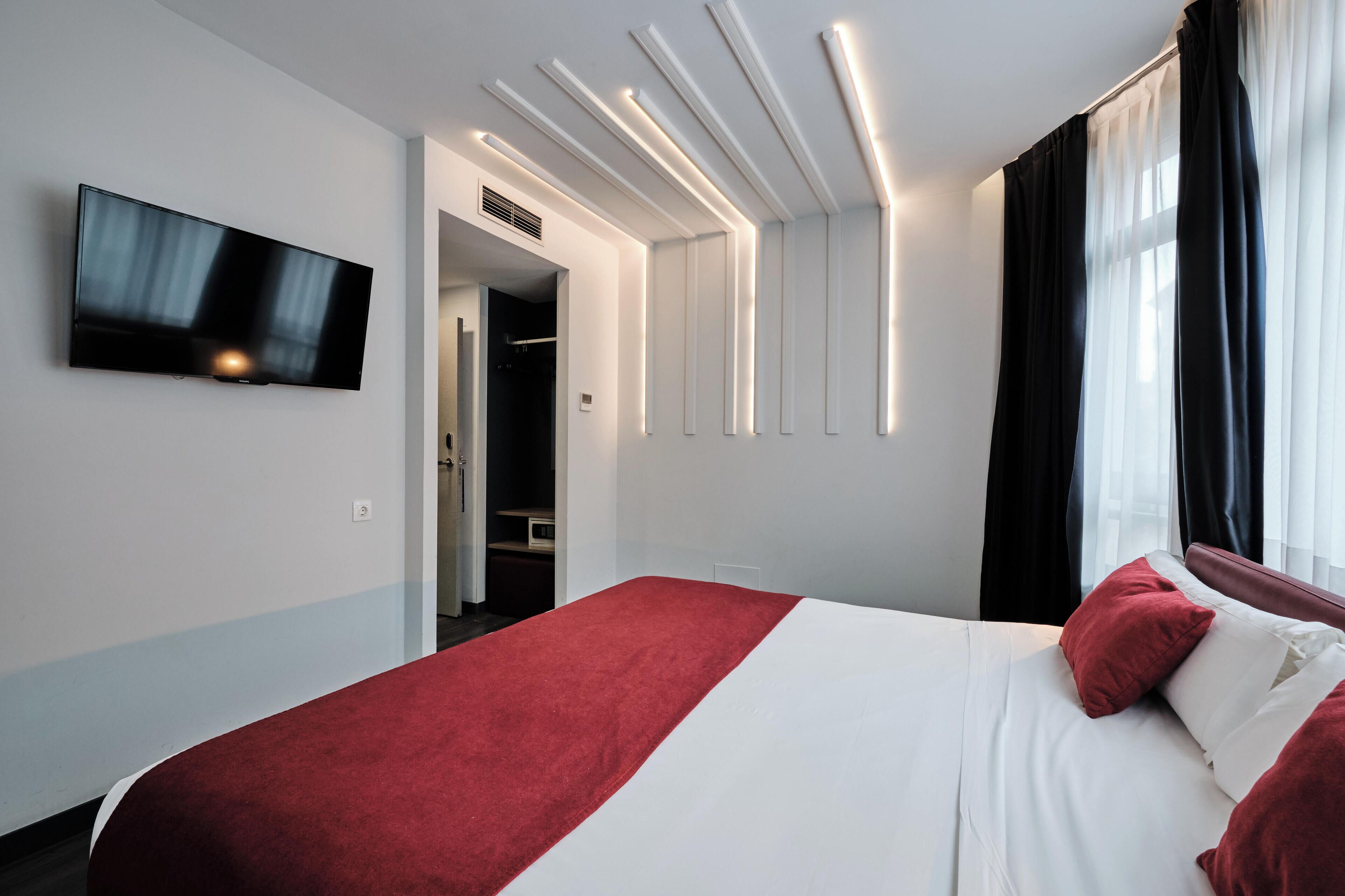 Habitació d'hotel moderna amb un llit gran, televisió de pantalla plana penjada a la paret i un armari encastat.