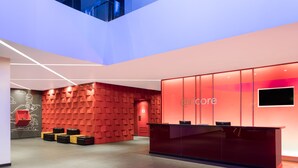 Un área de recepción moderna con una pared de acento roja, un mostrador de recepción y un televisor de pantalla plana.