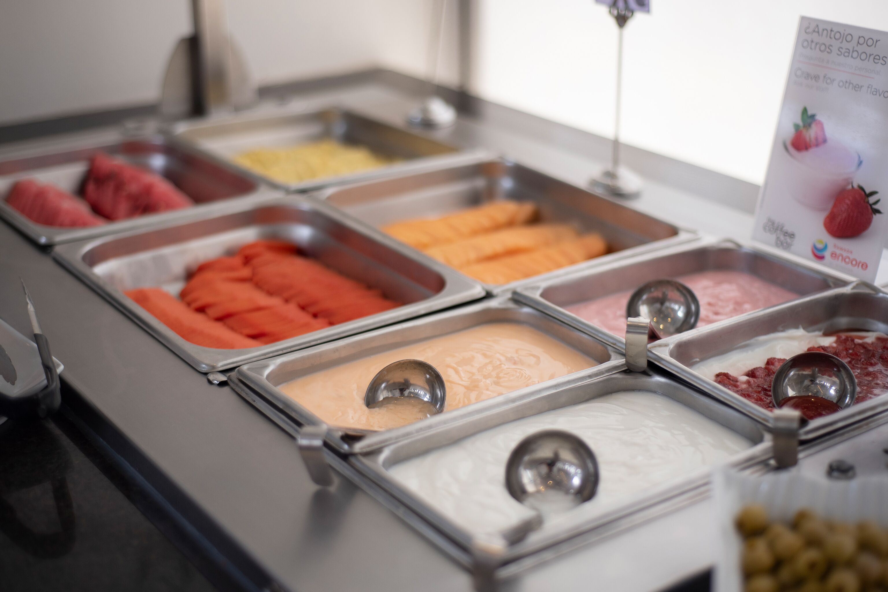 Un bufé con diversas opciones de comida en recipientes metálicos.