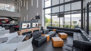 Un área de estar moderna con sofás, mesas y una pantalla de televisión mostrando FIFA23.