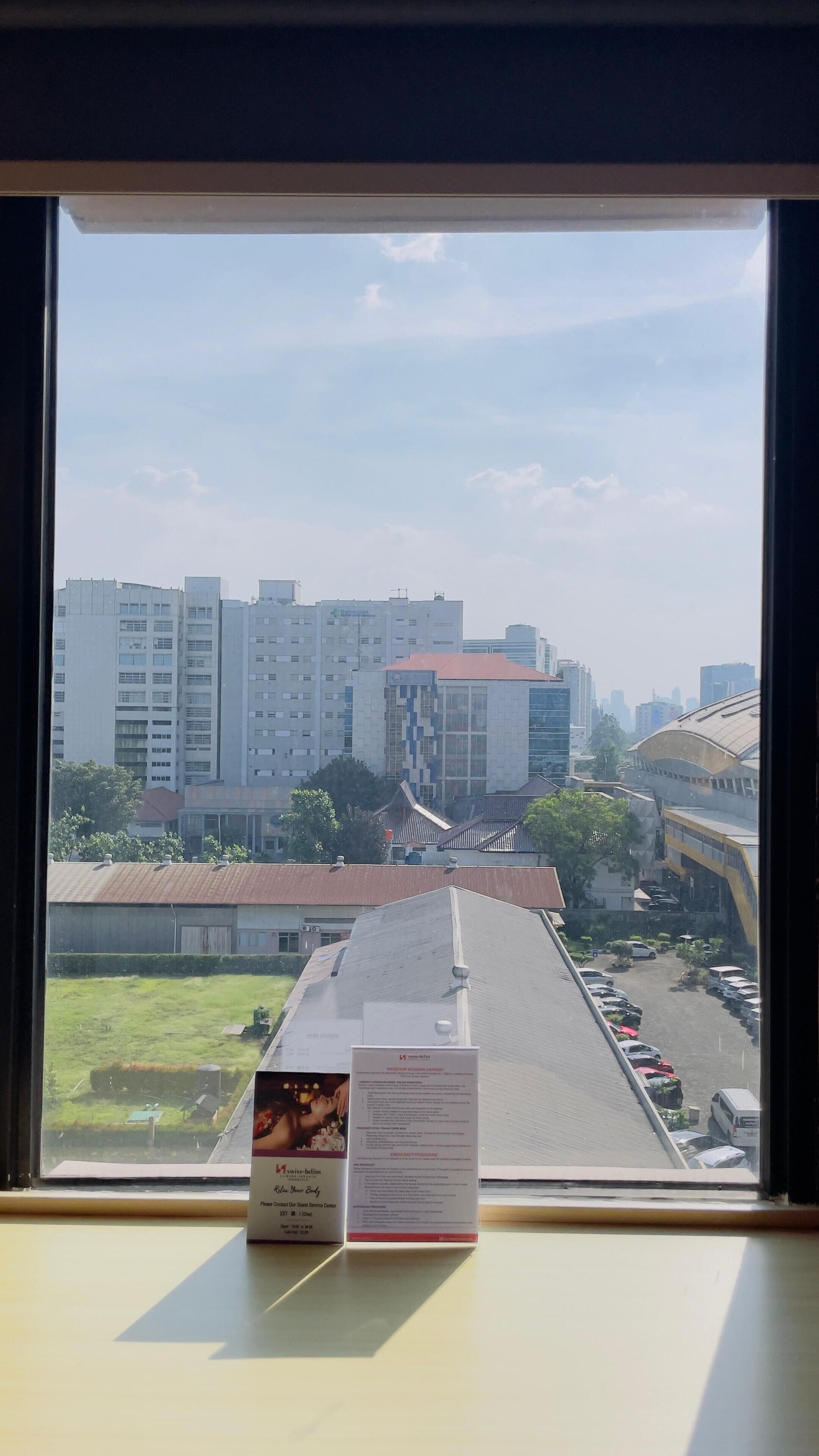 Una vista attraverso una finestra che mostra un parcheggio e diversi grattacieli sullo sfondo.