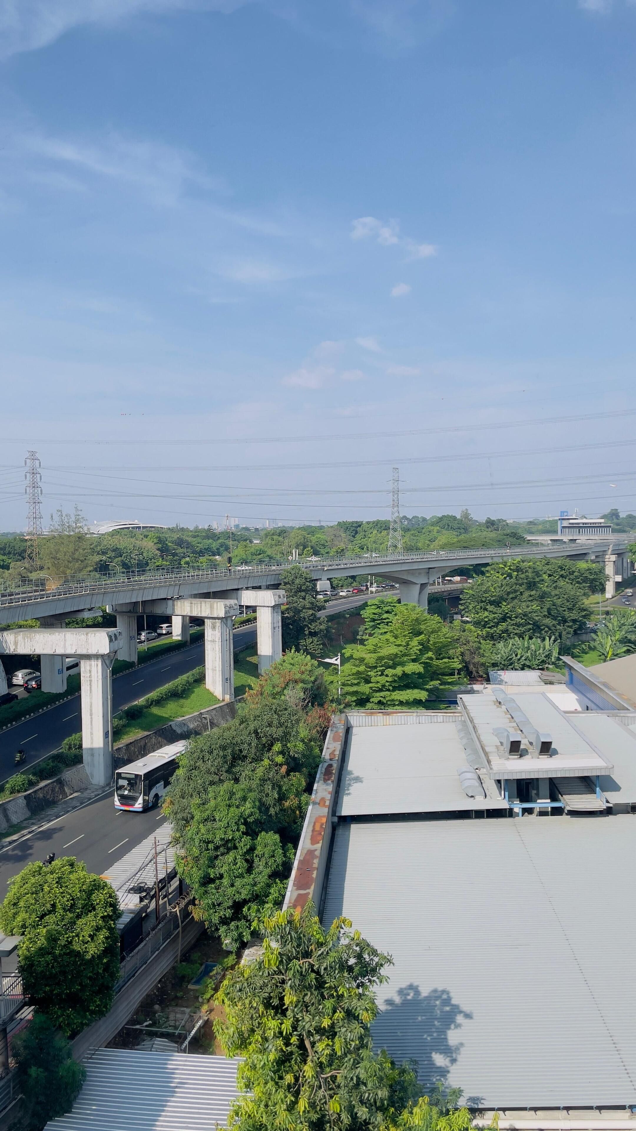 A multi-level highway with overpasses, a bus on the road, and greenery around.