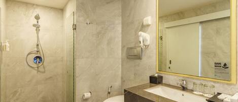 A modern bathroom with a glass-enclosed shower, a white toilet, and a marble sink with a large mirror.